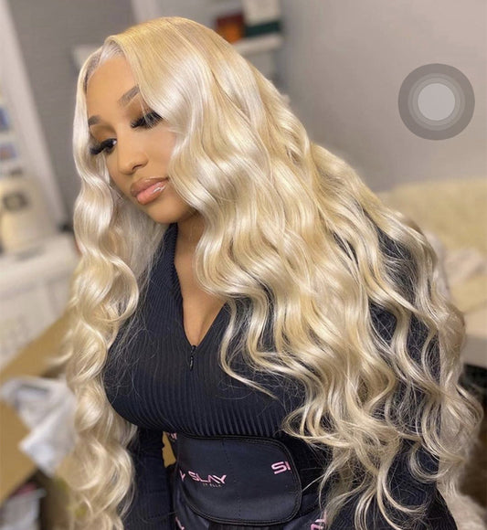 A person wearing a light gold long curly wig with voluminous big waves and long bangs.