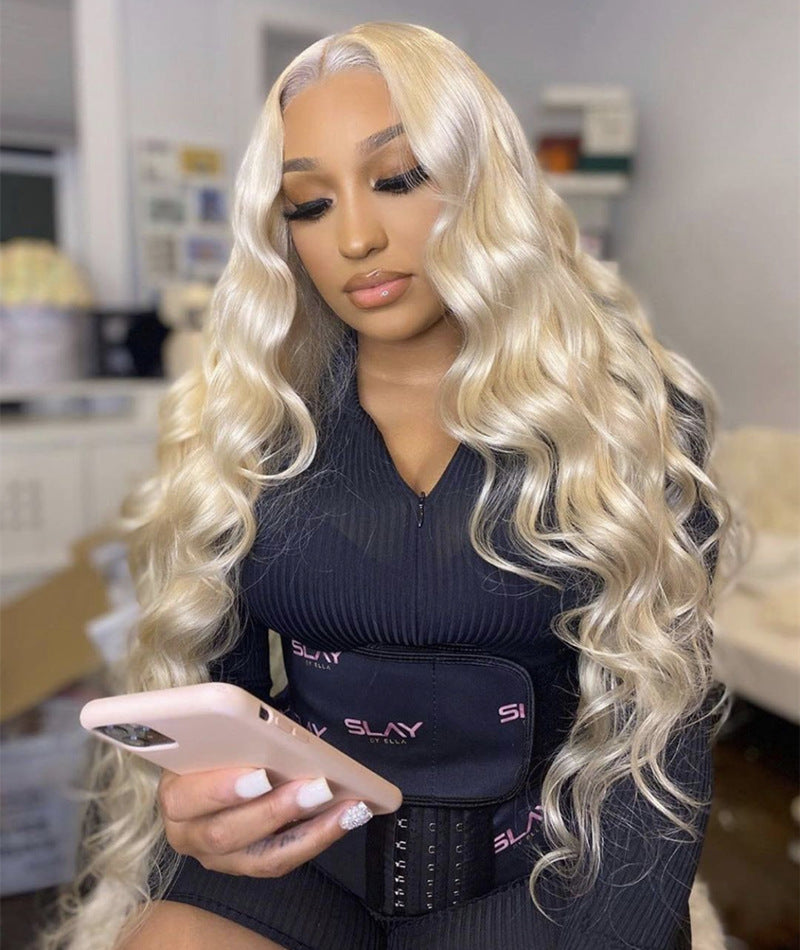 A person wearing a light gold long curly wig with voluminous big waves and long bangs.